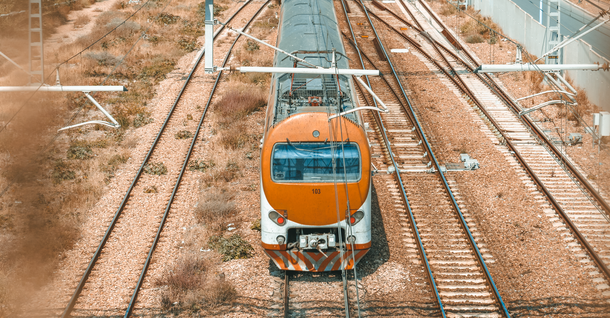 Aerial shot of an orange train on tracks in a rural setting, showcasing transportation and infrastructure.