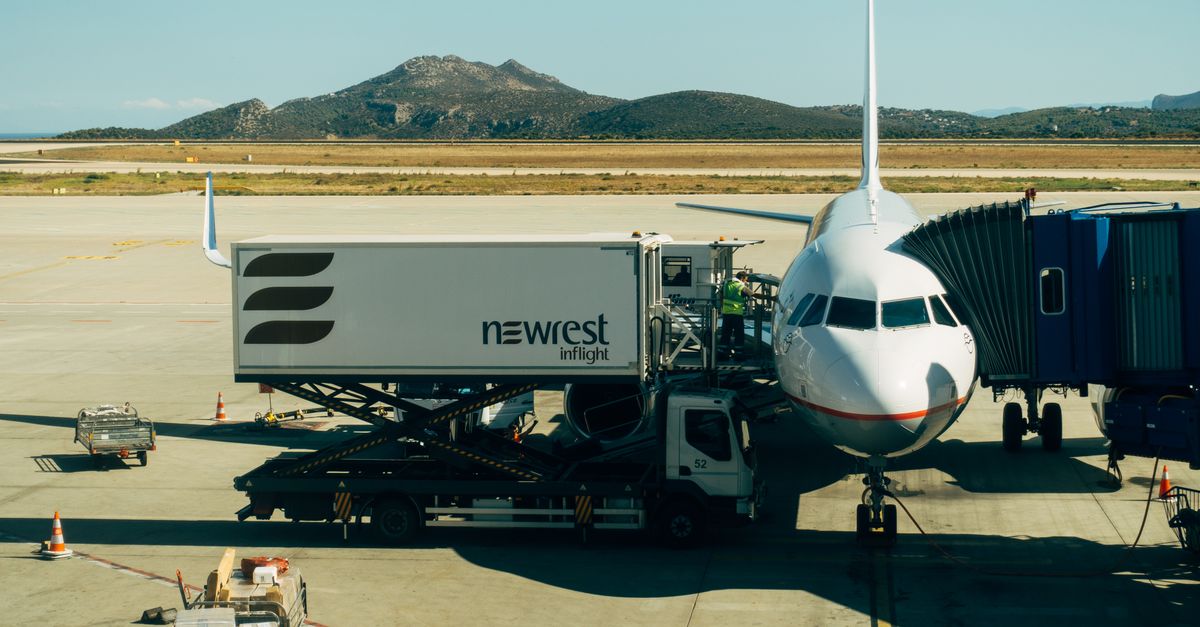 A commercial airplane being serviced at an airport with fueling and loading equipment.